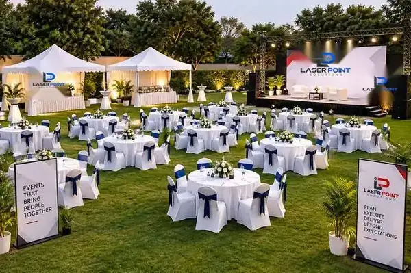 Full outdoor gala setup with round tables, stage and branded standees